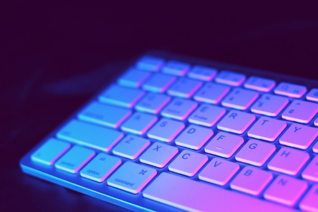 Terms and Conditions Close-up of a modern keyboard illuminated with vibrant purple and blue neon lighting.